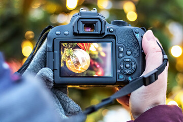 The girl takes pictures of the Christmas lights with the camera. Festive New Year's night streets.