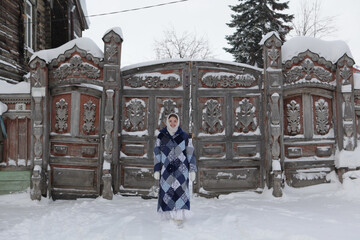 Wall Mural - Russian girl and carved gate, door of old wooden house in Solyanoy Lane, 18, Tomsk city, Russia. Russian folk style in architecture, fashion. Cold season, snow, snowy winter. Tomsk landmark, monument