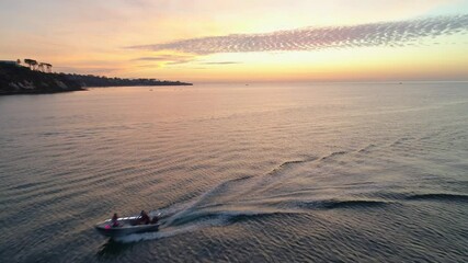 Wall Mural - Forward flight over boat and calm bay water near coastline at sunset