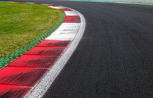 Close Up Of Dirtyt Curb At Left Turn On Motor Sport Track With Green Field And Black Asphalt