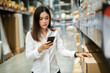 © geargodz - woman worker using smartphone to checking inventory in warehouse store