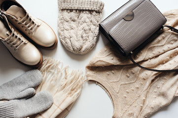 winter fashion set of woman clothes in neutral tones: warm sweater, hat, mittens, shoes and handbag 