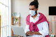 © Drobot Dean - Focused african american guy in face mask using laptop