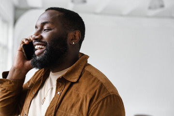 Cheerful african american man smiling and talking on mobile phone