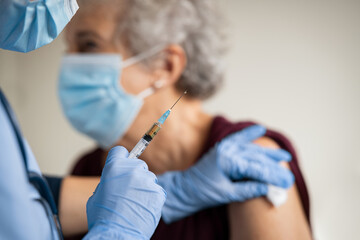 doctor makes vaccination to senior woman with surgical mask