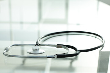 Black stethoscope lies on a glass table