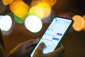 Close up of female hands holding mobile phone exchanging text messages.