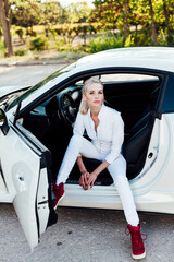 Beautiful female blonde driver behind the wheel of a white car