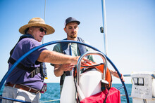 Man Learning How To Navigate During A Family Sail On Sunny Summer Day