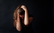 © Cavan Images - Distressed woman with long brown hair holding her head in her hands.