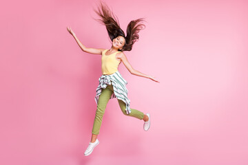 Poster - Full length photo of positive cheerful child girl dressed casual outfit jumping hands arms sides isolated pastel pink color background