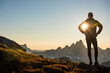 © Cavan Images - Sun shines through arm of silhouetted hiker on mountain ridge