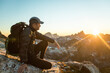 © Cavan Images - Fit active man sitting on rocky mountain ridge watching the sunset.