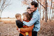 © Cavan Images - Fashionable young family hugging in a field on a cool autumn evening