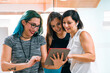 © Cavan Images - 3 young women are looking at a tablet