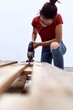 © Cavan Images - A young woman cutting wooden pallets with a jigsaw