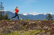 © Cavan Images - Side view of strong sportswoman running against snowy mountain ridge during fitness workout in countryside