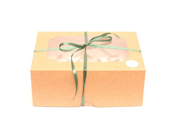 Craft gift box with a transparent top tied with a green ribbon on a white background. Studio photo of a gift from an angle