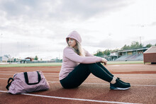 Woman Sat On A Running Track With A Sports Bag Waiting