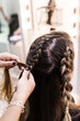 © Cavan Images - Hairdresser making braids to a young client at Hairdresser salon