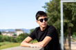 © Cavan Images - Young guy with sunglasses leaning on wall while looking away