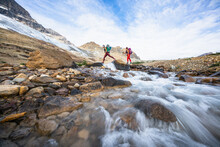 Female Backpackers Crossing River While Hiking Beautiful Iceline Trail