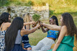 © Cavan Images - Group of women friends drinking beer in a park on summer day