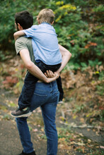 Little Boy Being Carried On His Father's Back During Their Hike