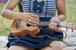 © Cavan Images - Close-up of a woman playing ukelele with a group of friends