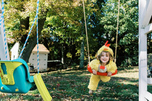 Little Girl In Chicken Costume On A Swing In Fall