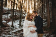 © Cavan Images - Husband and pregnant wife in the forest on a snowy sunny winter day