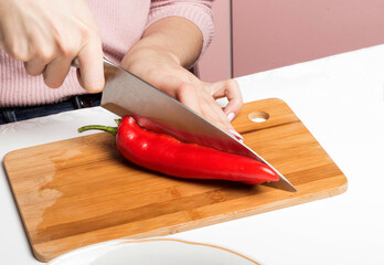 a woman cuts sweet peppers on a salad cutting Board