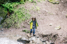 High Level View Boy Climbing Over Rocks By River At Waterfall