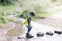 Child Walking On Stones Crossing A River