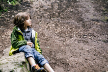Close Up Side View Boy Sitting Over Moss Rock Looking Away