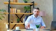 © viacheslav - Businessman sitting on chair at table in home office puts on case wireless earphones. Gray-haired man using laptop computer connects to remote online video chat conference call with company employees