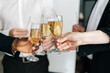 © dikushin - Close-up view of business team of multinational employees holding clinking glasses of champagne and smiling cheerfully at corporate New Year or Happy Christmas eve.