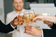 © dikushin - Close-up view of business team of multinational employees holding clinking glasses of champagne and smiling cheerfully at corporate New Year or Happy Christmas eve.