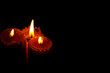 © mihail39 - Close-up of three small yellow candles on a black background.
