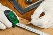© fusssergei - A carpenter with a pencil and tape measure measures a wooden Board on the table
