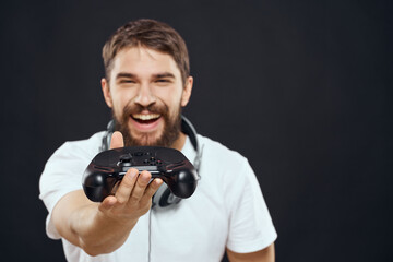 Wall Mural - Man with joystick in hands headphones technology leisure game lifestyle dark isolated background