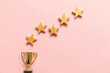Simply flat lay design winner or champion gold trophy cup and 5 stars rating isolated on pink pastel background. Victory first place of competition. Winning or success concept. Top view, copy space