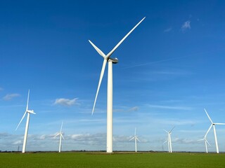 Wind turbines that produce electricity energy. Windmill Wind power technology productions Wind turbines standing on a blooming fields in green field. 