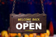 Welcome back we are open sign hanging outside a shop after lockdown