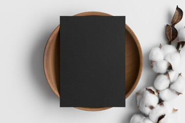 Canvas Print - Black invitation card mockup on a wooden plate with a dried cotton branch. 5x7 ratio, similar to A6, A5.