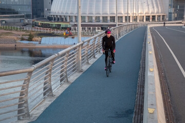 Wall Mural - Woman training on a bicycle in the city at dawn. Yacht bridge St. Petersburg