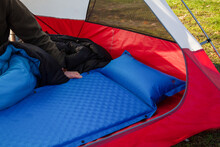 A Man Gets His Tent And Sleeping Bag Ready At A Campground By Inflating And Setting Up His Blue Blow-up Mattress Pad To Put For Under His Sleeping Bag