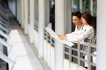 Couple travelers holding a paper map in hands together and looking and finding destination and station for lines of a sky train with a blurry background. Idea for tourists travels on vacation