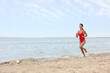 © New Africa - Beautiful female lifeguard running at sandy beach