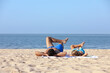 © New Africa - Father and son lying on sandy beach near sea. Summer holidays with family
